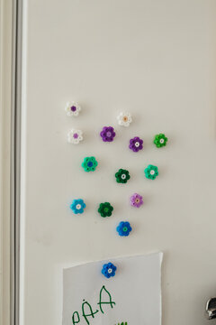 Handmade colorful magnets made out of iron pearls hanging on a white fridge