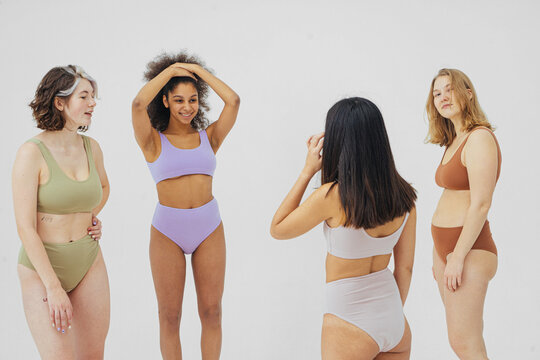 group of multiracial women in colored underwear on gray background