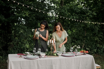 Young Women Arranging Flowers and Fruit for Backyard Dinner