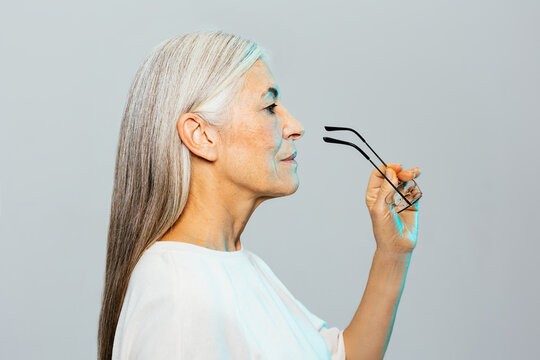 Smart aged female putting on glasses