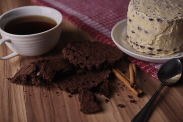Brownie slices, buttercream cake, and a cup of coffee with cinnamon sticks on the table.