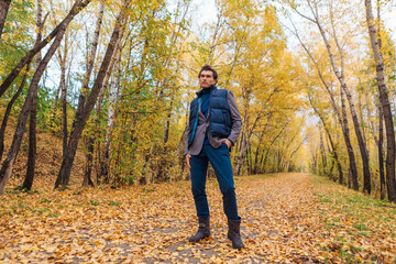 Fototapeta premium Tall handsome man walking in the autumn alley