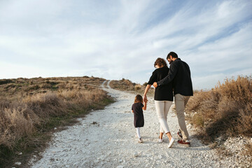 A young family with a little daughter on a walk.