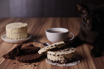 Brownie slices with buttercream on the table against the background of the cat lying there.