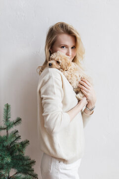 Happy woman is holding a little puppy on the shoulder