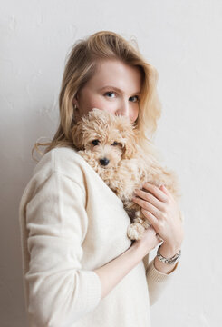 Happy woman is smiling and hugging little puppy 