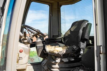 Old empty shabby driver's seat in the cab of a tractor, crane or other agricultural or construction...
