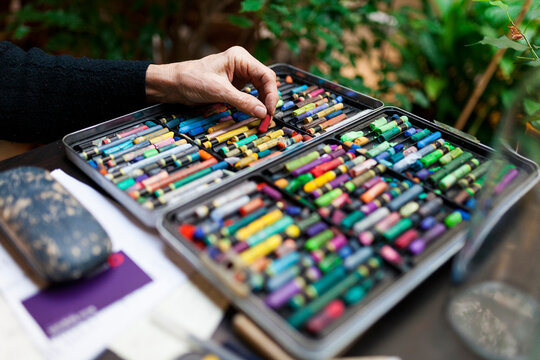 artist hand picking a crayon from crayon case