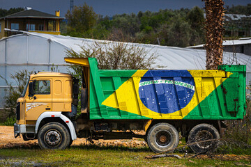 Dump truck with the image of the national flag of Brazil is parked against the background of the...