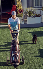 Hombre practicando swing de golf, con su carro y palos - obrazy, fototapety, plakaty