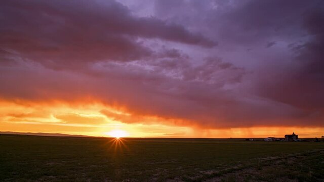 Colorful sunset timelapse with farmhouse over the flat plains in Wyoming.