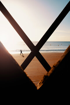 Silhouette of a man running along the beach, with an X in the foreground.