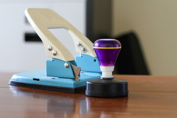 Blue perforator and purple manual stamp which are office equipment as tools in administrative work
