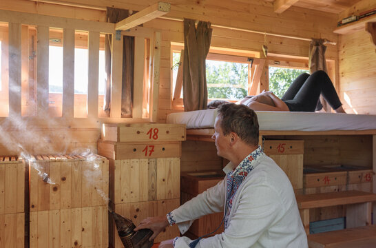 Man smoking bees near woman during apitherapy session