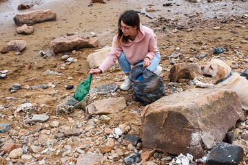 Dog owner collecting litter on seashore