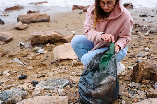 Young woman collecting litter near sea