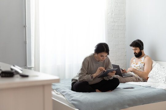 Man and woman browsing gadgets on bed