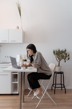 Young female using netbook in morning in kitchen