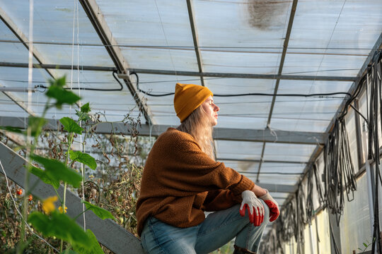 Young female gardener relaxing in glasshouse