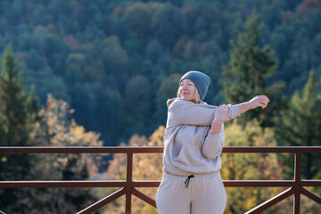 Sportswoman stretching arm near forest
