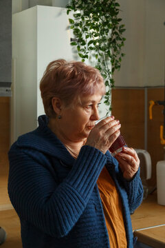 Aged female drinking in kitchen