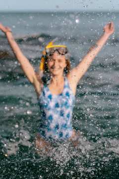 Happy female swimmer playing with sea water