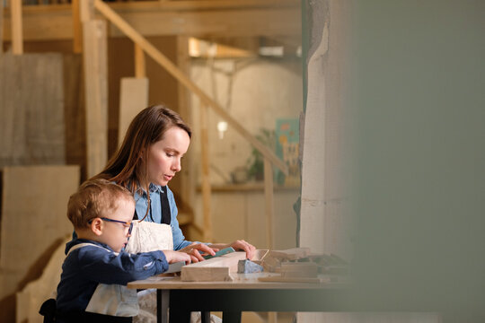 Mother and little son constructing wooden toy