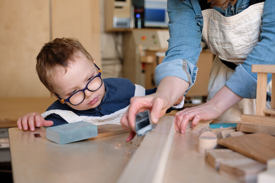 Little kid learning carpentry craft with mom