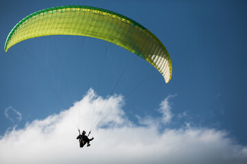 Unrecognizable person paragliding in blue sky