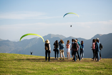 Tourists watching paragliders flying in mountains