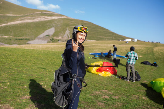 Happy woman with camera ready to paraglide
