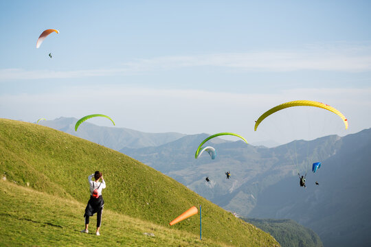 Traveler on hill watching at paragliders in mountains