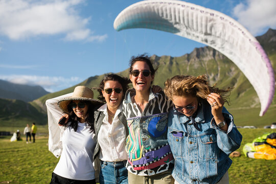 Young women hugging and laughing during paragliding festival