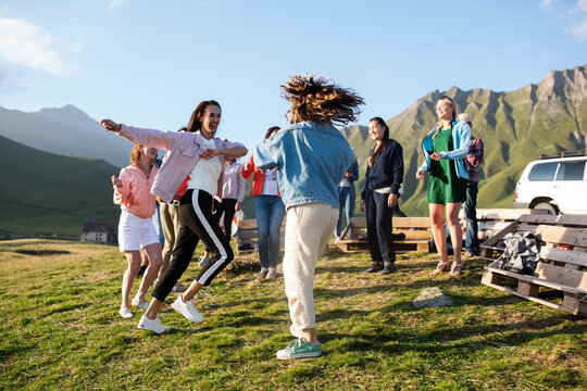 Cheerful girlfriends dancing in countryside