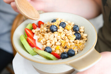 Hand of woman holding bowl of fresh strawberry and yogurt .Concept of healthy diet and weight control.soft focus