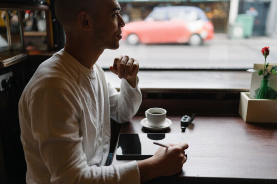 Man Drinking a Coffee and Working from a Coffee Shop