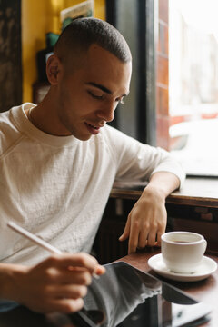 Young Man Using Computer Seated in a Coffee Shop