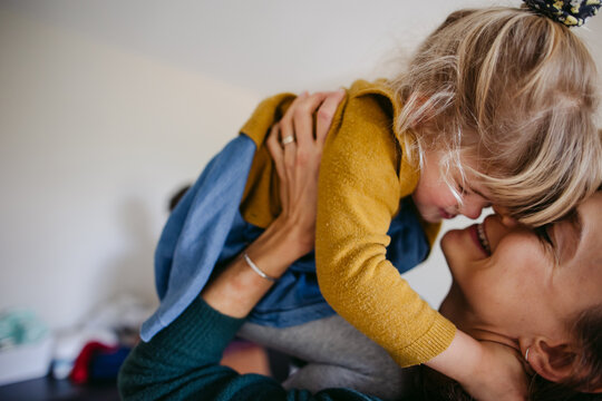 Fun loving mom playing with daughter at home.