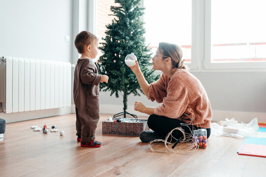 Mom showing Christmas ornament to toddler