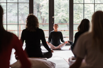 Female instructor breathing and meditating with group