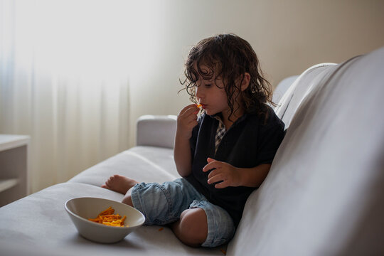 Funny portrait of a three year old boy with snack in his mouth