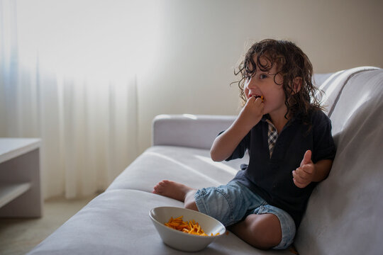 Funny portrait of a three year old boy with snack in his mouth