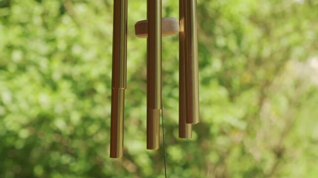 Metal wind chime natural green background slow motion 120p