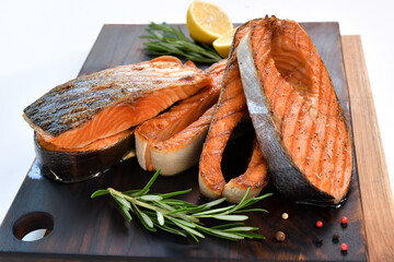 Grilled salmon steaks with ingredients on wooden cutting board in the kitchen
