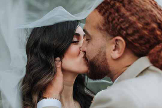 Beautiful Bride and Groom Kissing under Veil