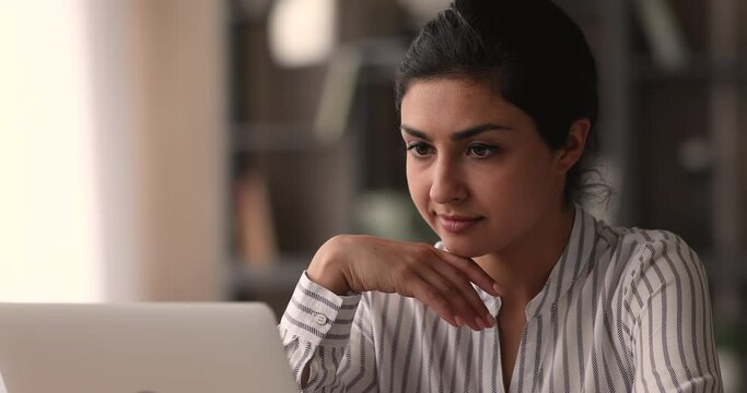 Indian ethnicity woman working on laptop, close up. Attractive young female student prepare for exams, do assignment using internet web sites. Remote telecommuting, modern technology usage concept
