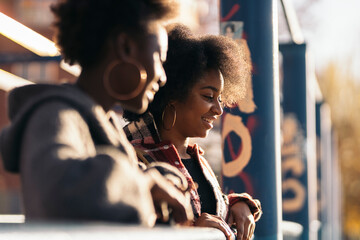 Two african girls together holding the railing, looking aside