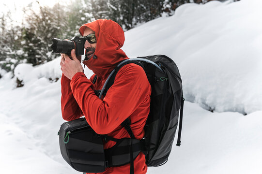 Hiker taking pictures with digital camera in snowy mountain
