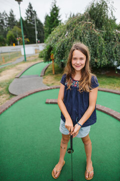 Girl smiles at camera while playing mini golf