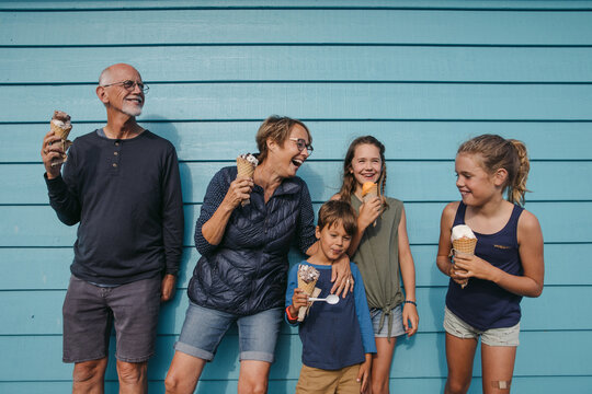 Grandparents and grandkids laugh and lean against a wall and enj